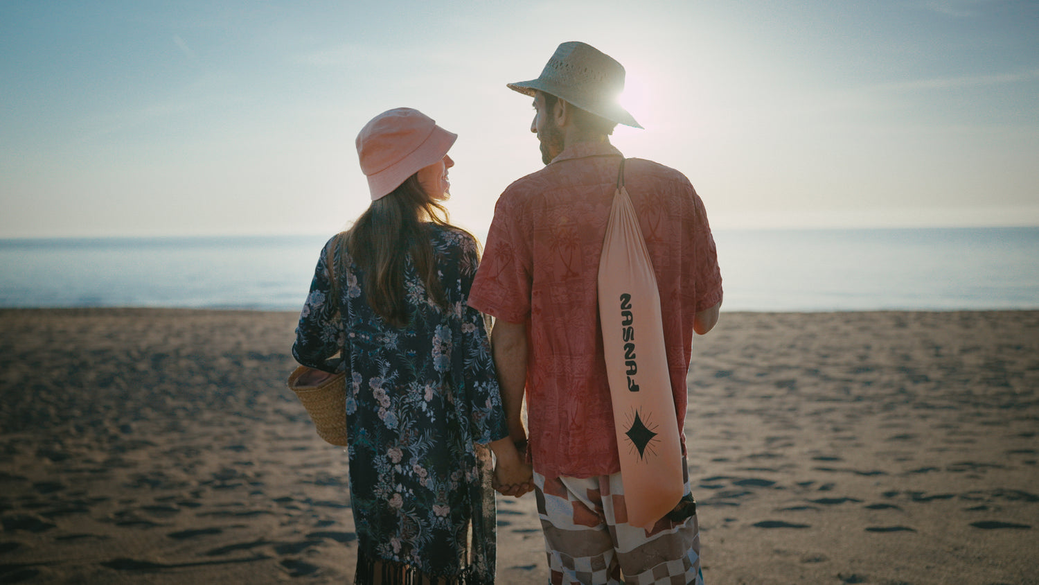 A young couple from the back with a FunSun package at sunset